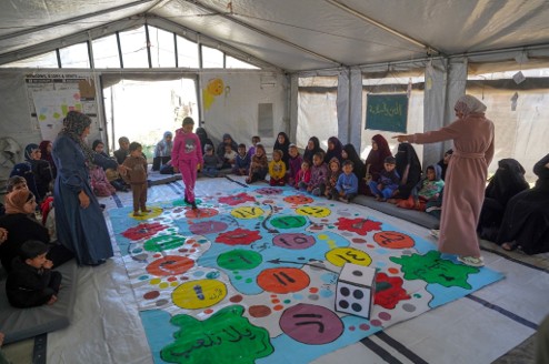 Child engaging in a learning through play activity, supported by two facilitators, Gaza, 2026 | Credit: Palm Media, Right To Play 