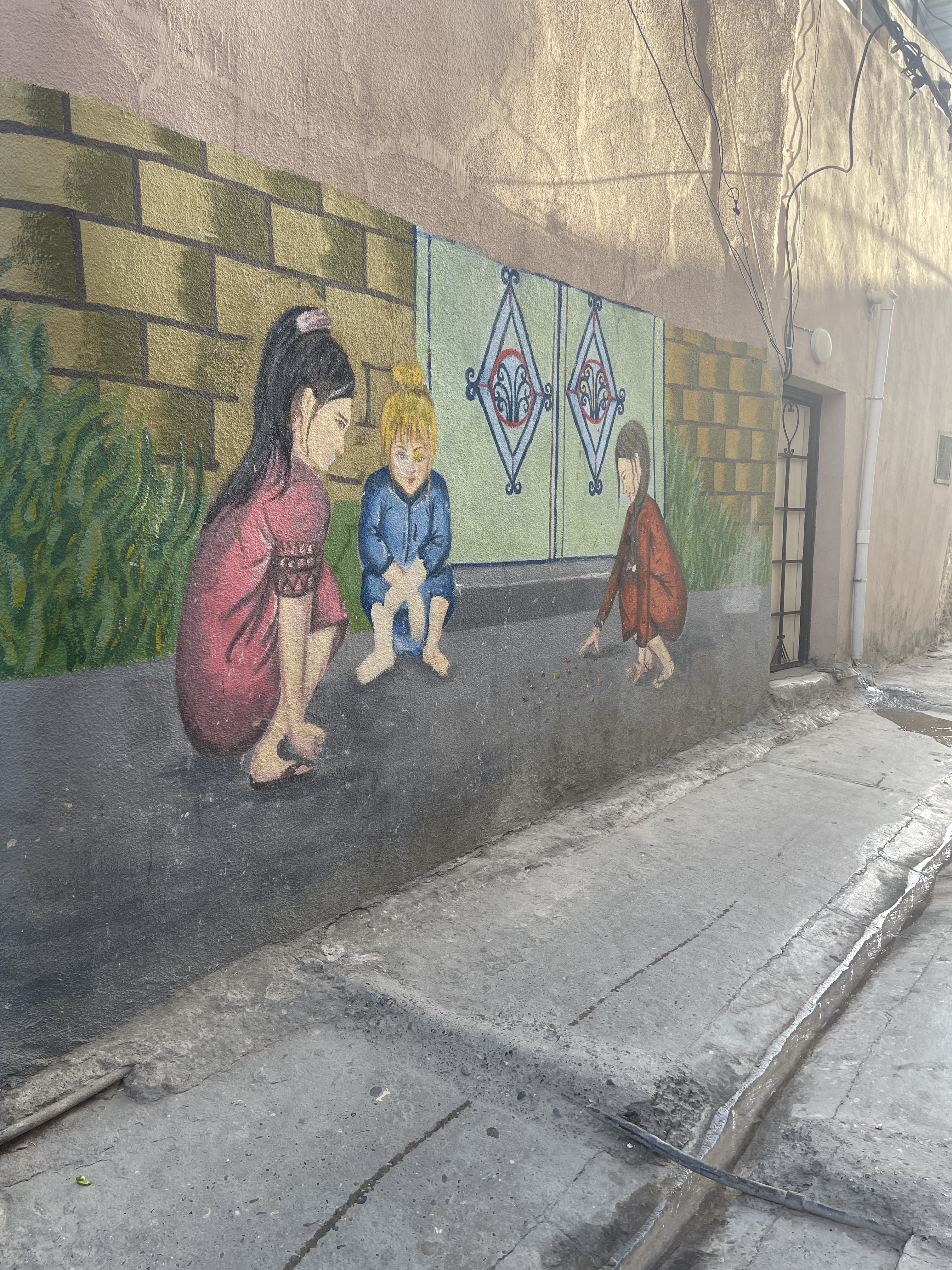 A mural of children playing on the side of a city building.