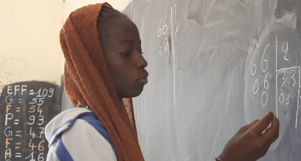 Student Aminata L. Ballayira from Soungola village writing on the classroom board.
