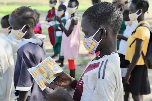 child with a mask on reading a pamphlet